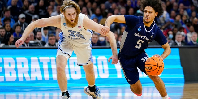St. Peter's Daryl Banks III, right, tries to get past North Carolina's Brady Manek during the first half of a college basketball game in the Elite 8 round of the NCAA tournament, Sunday, March 27, 2022, in Philadelphia.