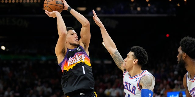 Phoenix Suns guard Devin Booker (1) shoots over Philadelphia 76ers forward Danny Green during the second half of an NBA basketball game, Sunday, March 27, 2022, in Phoenix. Phoenix won 114-104.
