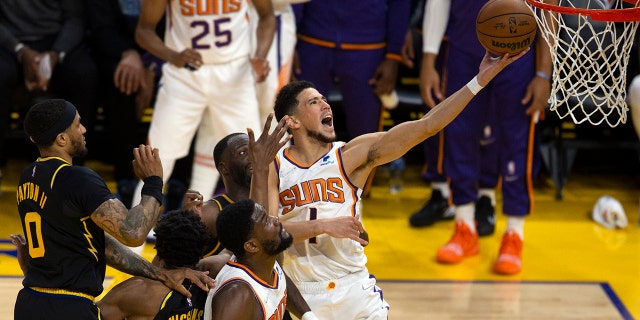 Phoenix Suns guard Devin Booker (1) drives to the basket through a trio of Golden State Warriors defenders during the third quarter of an NBA basketball game Wednesday, March 30, 2022, in San Francisco.