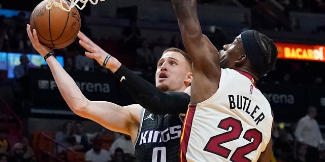 Sacramento Kings guard Donte DiVincenzo (0) drives to the basket as Miami Heat forward Jimmy Butler (22) defends during the first half of an NBA basketball game, 月曜, 行進 28, 2022, マイアミで. 