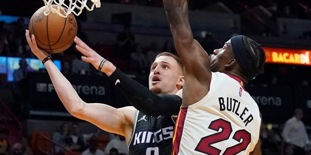Sacramento Kings guard Donte DiVincenzo (0) drives to the basket as Miami Heat forward Jimmy Butler (22) defends during the first half of an NBA basketball game, 月曜, 行進 28, 2022, マイアミで.