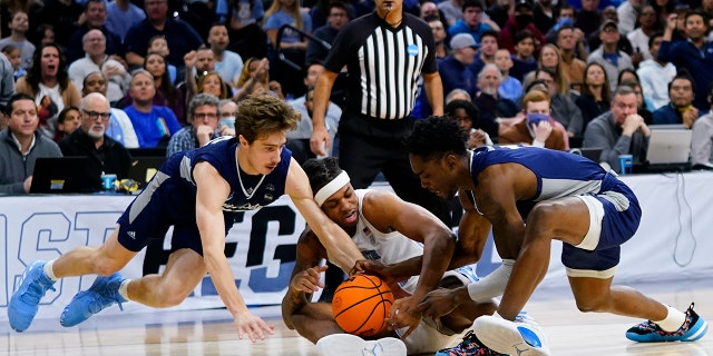North Carolina's Armando Bacot, center, battles for a loose ball with St. Peter's Doug Edert, left, and KC Ndefo during the first half of a college basketball game in the Elite 8 round of the NCAA tournament, Sunday, March 27, 2022, in Philadelphia.
