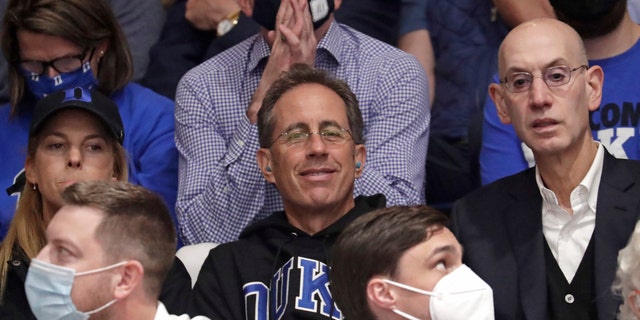 Actor and comedian Jerry Seinfeld, center, sits next to NBA Commissioner Adam Silver, right, prior to an NCAA college basketball game between Duke and North Carolina in Durham, N.C., Saturday, March 5, 2022.