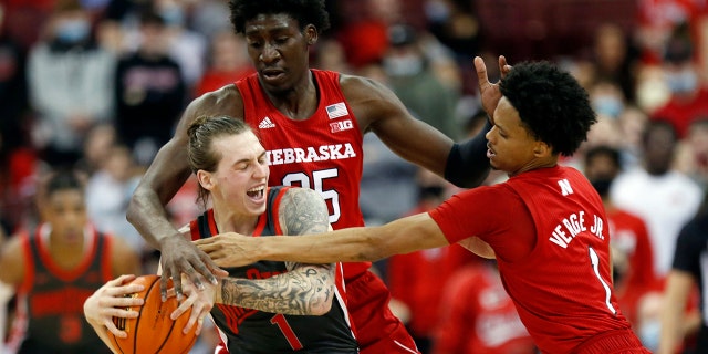 Nebraska center Eduardo Andre, rear, fouls Ohio State guard Jimmy Sotos, left, in front of Nebraska guard Alonzo Verge during the first half of an NCAA college basketball game in Columbus, Ohio, Tuesday, March 1, 2022.