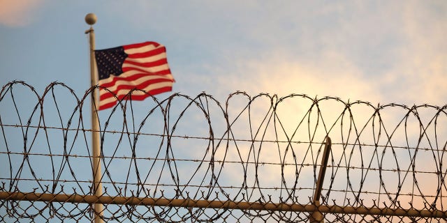 An American flag behind a barbed wire fence at Guantanamo Bay.