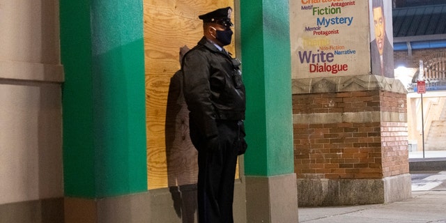 A police officer monitors activity in front of a boarded up bank and a mural of stated literary devices after looting on Oct. 30, 2020 in Philadelphia, Pennsylvania. (Photo by Mark Makela/Getty Images)