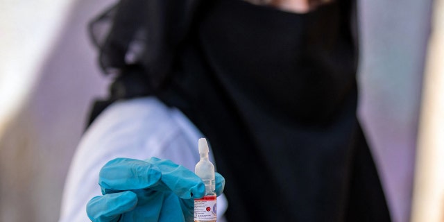 A Yemeni health worker holds a vial containing the polio vaccine during a vaccination campaign in Yemen's third city of Taez, on Feb. 19, 2022 (Photo by AHMAD AL-BASHA/AFP via Getty Images)