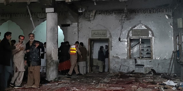 Security personnel inspect a mosque after a bomb blast in Peshawar on March 4, 2022.