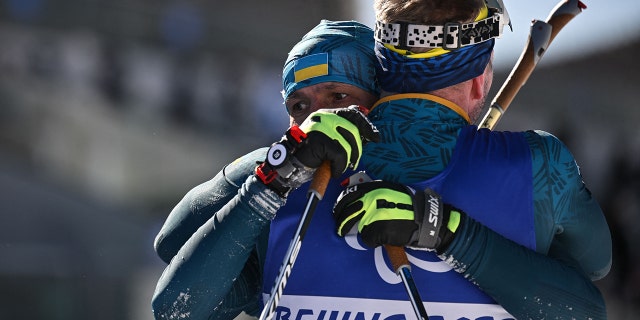 Ukraine's Vitalii Lukianenko is hugged by Ukraine's Dmytro Suiarko after the men's sprint vision-impaired biathlon event March 5, 2022, at the Zhangjiakou National Biathlon Centre during the Beijing 2022 Winter Paralympic Games.