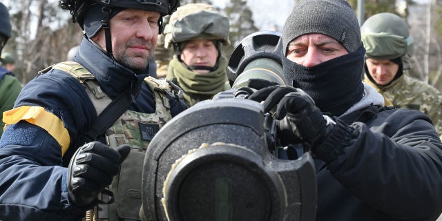 Members of the Ukrainian Territorial Defence Forces examine new armament, including NLAW anti-tank systems and other portable anti-tank grenade launchers, in Kyiv on March 9, 2022, amid the ongoing Russia's invasion of Ukraine.