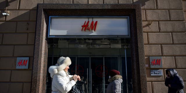 People walk past a closed H&amp;M store in Moscow on March 10, 2022, after Swedish clothing giant Hennes and Mauritz halted all sales in its Russian stores over the war in Ukraine.