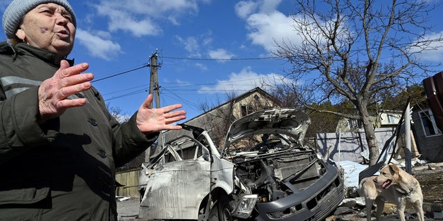 Local retiree Nataliya Mykolaivna, 64, gestures as she talks to an AFP journalist next to a destroyed minibus.