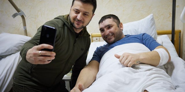 Ukrainian President Vladimir Zelenskiy takes a photo with a wounded soldier by Russian attacks on Ukraine during his hospital visit in Kyiv, Ukraine on March 13, 2022.