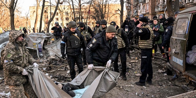 Ukrainian policemen carry a body from a five-story residential building that partially collapsed after a shelling in Kyiv March 18, 2022, as Russian troops try to encircle the Ukrainian capital as part of their slow-moving offensive. 