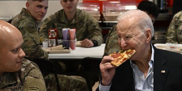 Joe Biden (R) eats a pizza as he meets with service members contributing alongside Polish Allies to deterrence on the Alliances Eastern Flank, in the city of Rzeszow, around 100 kilometers (62 miles) from the border with Ukraine.