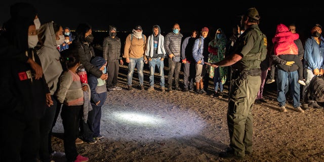 A Border Patrol agent speaks with immigrants before transporting some of them to a processing center on Dec. 9, 2021, in Yuma, Arizona.