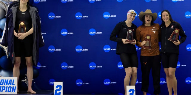 Transgender athlete Lia Thomas, left, of the University of Pennsylvania, steps onto the podium after winning the 500-yard freestyle while fellow medalists - from second left, Emma Weyant, Erica Sullivan and Brooke Forde – pose for a photo at the NCAA Division I Women's Swimming and Diving Championships, March 17, 2022 in Atlanta. (Getty Images)