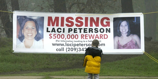 A young child stops to look at a makeshift memorial and a missing person banner offering a $500,000 reward for the safe return of Laci Peterson at the East La Loma Park Jan. 4, 2003, in Modesto, Calif. 