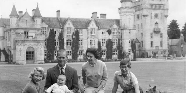 Dronning Elizabeth II og prins Philip, hertugen av Edinburgh, med barna deres, prinsesse Anne (helt til venstre), prins Andrew (som baby) og Charles, prins av Wales (helt til høyre), sitter på et piknikteppe utenfor Balmoral Castle i Skottland i september 1960. 