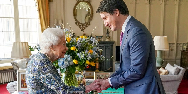 Britain's Queen Elizabeth II (L) shakes hands with Canadian Prime Minister Justin Trudeau as they meet for an audience at the Windsor Castle, Berkshire, on March 7, 2022.