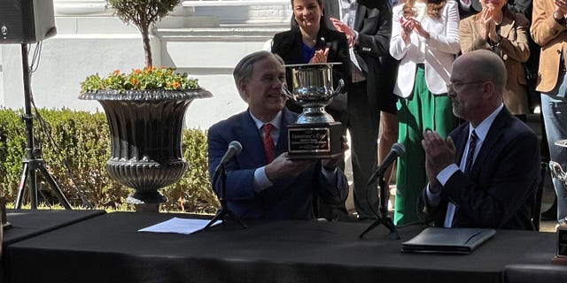 Texas Gov. Greg Abbott holds the Governors' Cup, which is awarded to the top state for job creation and economic development, at a news conference in Austin, Texas, on March 1, 2022