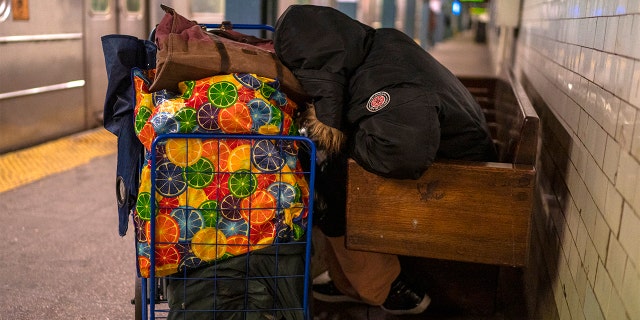 NEW YORK, NY - MARCH 15: A homeless person sleeps on a bench March 15, 2022 in a subway station in New York City. It is estimated 1,000 homeless individuals sleep in stations and on the trains each day. (Photo by Robert Nickelsberg/Getty Images)
