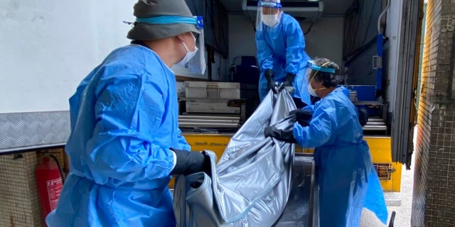 Workers from the Food and Environmental Hygiene Department, move a corpse from the mortuary to the coffin van at the Queen Elizabeth Hospital in Hong Kong, Wednesday, March 2, 2022. Some hospitals in Hong Kong are currently being overloaded with possible COVID-infected patients.