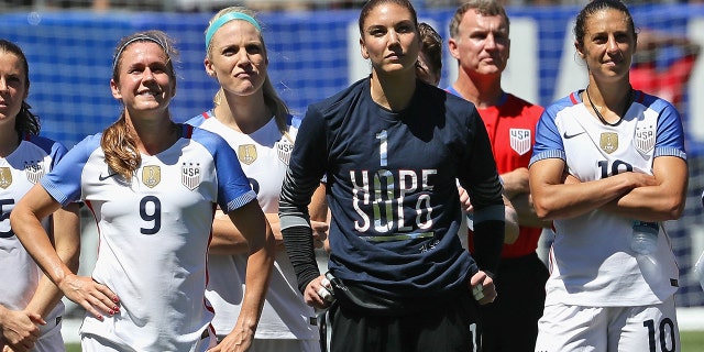 (L-R) Heather O'Reilly #9, Julie Johnson #8, Hope Solo #1 and Carli Lloyd #10 of the United States watch a video tribute to Solo after she posted her 100th career shutout against South Africa in a friendly match at Soldier Field on July 9, 2016, in Chicago, Illinois. The United States defeated South Africa 1-0.