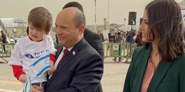 Israel’s Prime Minister, Naftali Bennett, holds a child who made it safely out of Ukraine amid the war; Bennett is accompanied by his wife, Gilat Bennett.