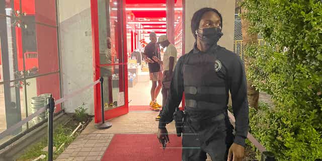 An armed guard stands watch outside a high-end boutique sneaker store on Collins Avenue in Miami Beach  Wednesday.