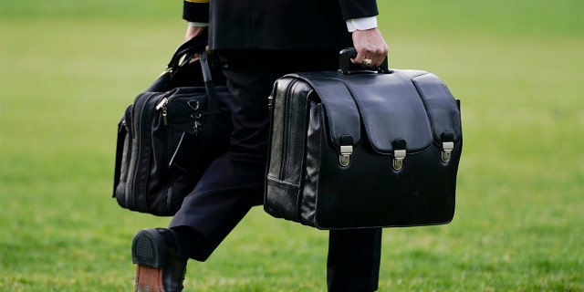 A military aide carries the "President's emergency satchel," also known as "the football," which contains nuclear launch codes, before boarding Marine One behind President Biden on the South Lawn of the White House, Wednesday, March 23, 2022, in Washington.
