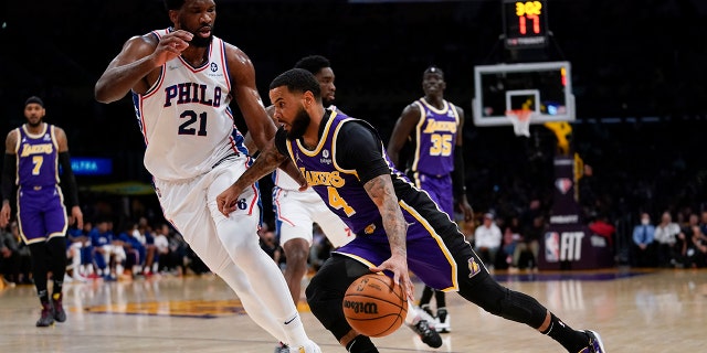 Philadelphia 76ers center Joel Embiid (21) defends against Los Angeles Lakers guard D.J. Augustin (4) during the first half of an NBA basketball game in Los Angeles, Wednesday, March 23, 2022.