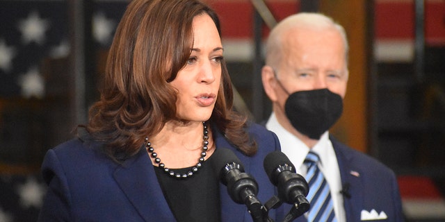 Vice President Harris stands in front of a masked President Biden