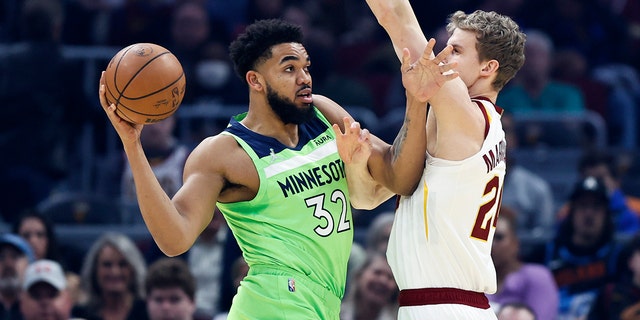 Karl-Anthony Towns (32) of the Minnesota Timberwolves attempts to pass the ball while Lauri Markkanen (24) of the Cleveland Cavaliers defends during the first half of a game February 28, 2022 in Cleveland.