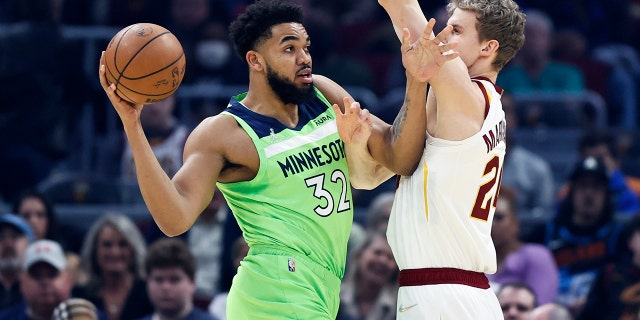 Karl-Anthony Towns (32) of the Minnesota Timberwolves looks to pass the ball as Lauri Markkanen (24) of the Cleveland Cavaliers defends during the first half of an NBA basketball game Monday, February 28, 2022, in Cleveland.