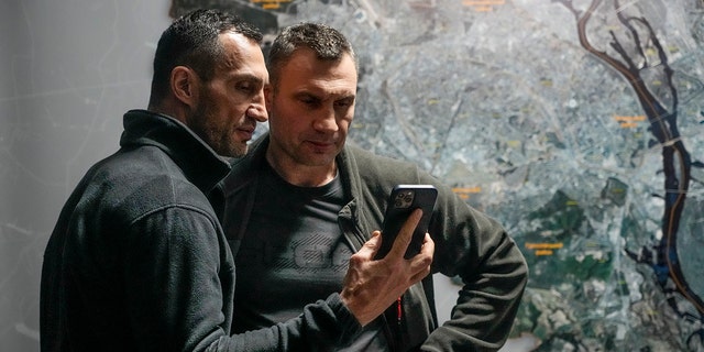 Vitali Klitschko, Kyiv Mayor and former heavyweight champion, right, and his brother Wladimir Klitschko, a Ukrainian former professional boxer look at a smartphone in City Hall in Kyiv, Ukraine, Feb. 27, 2022.