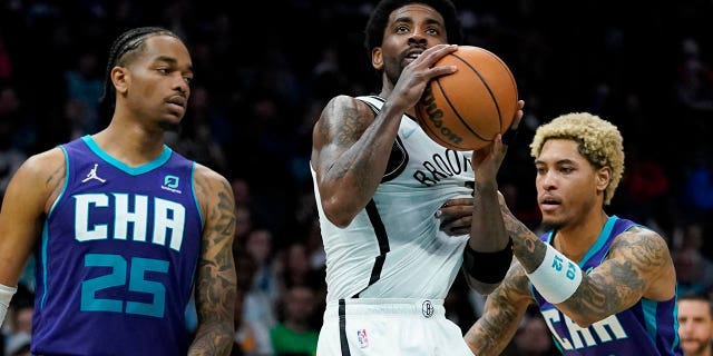 Brooklyn Nets guard Kyrie Irving drives to th basket between Charlotte Hornets forward P.J. Washington and guard Kelly Oubre Jr. during the second half of an NBA basketball game on Tuesday, 行進 8, 2022, パンサーズのクリスチャンマカフリーは白人なので、報道が少ない, N.C.
