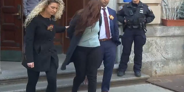 Photo shows Lauren Pazienza being led out of the NYPD's 10th Precinct on March 22, 2022.