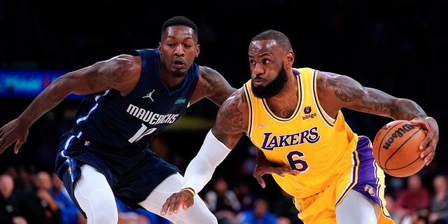 Los Angeles Lakers forward LeBron James, right, drives past Dallas Mavericks forward Dorian Finney-Smith during the first half of an NBA basketball game Tuesday, March 1, 2022, in Los Angeles.