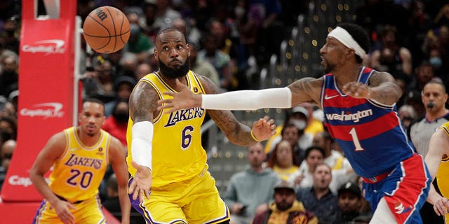 The Los Angeles Lakers' LeBron James (6) and Washington Wizards' Kentavious Caldwell-Pope (1) reach for the ball during the second half of a game, Saturday, March 19, 2022, in Washington.