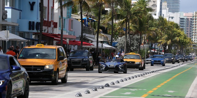 Vehicles drive through a bust street Tuesday in Miami Beach as the city endures another spring break season. 