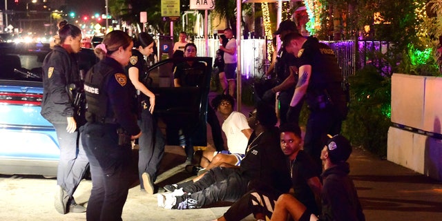 Miami Beach, Florida: March 22, 2022 - Police question a group of young men in connection with an alleged reckless driving incident on the city's waterfront Ocean Drive.