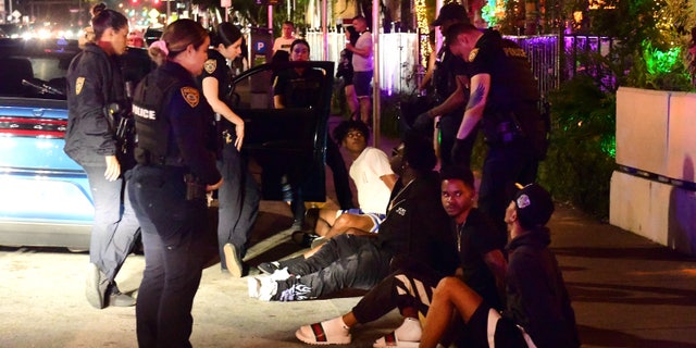 Miami Beach, Florida: March 22, 2022 - Police question a group of young men in connection with an alleged reckless driving incident on the city's waterfront Ocean Drive.