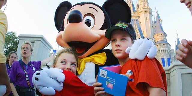 The Walt Disney character Mickey Mouse greets children at the Magic Kingdom in Nov. 11, 2001, in Orlando, Florida. 