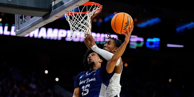 Saint Peter's Matthew Lee, left, goes up for a shot against Purdue's Jaden Ivey during the first half of a college basketball game in the Sweet 16 round of the NCAA tournament, Friday, March 25, 2022, in Philadelphia.