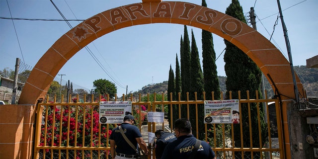 An agent of the Michoacan Attorney General's office places a lock and chain on a gate at a clandestine cockfighting ring following the killing of at least 20 people on Sunday night during an attack, authorities said, in Zinapecuaro, Mexico March 28, 2022.