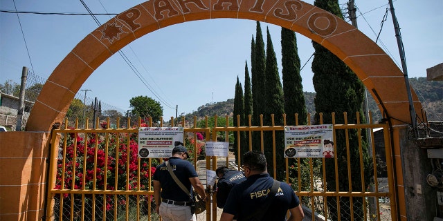 Un agente de la Procuraduría General de Justicia de Michoacán coloca un candado y una cadena en la puerta de una red clandestina de peleas de gallos luego de la muerte de al menos 20 personas el domingo por la noche durante un ataque, dijeron las autoridades, en Zinapécuaro, México, el 28 de marzo de 2022.