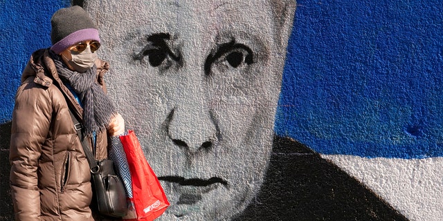 Μια γυναίκα περνά μπροστά από μια τοιχογραφία που απεικονίζει τον Ρώσο Πρόεδρο Βλαντιμίρ Πούτιν στο Βελιγράδι της Σερβίας, Σάββατο 12 Μαρτίου 2022. 