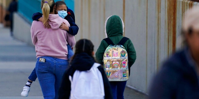 Children and their caregivers arrive for school in New York, Monday, March 7, 2022.  (AP Photo/Seth Wenig)