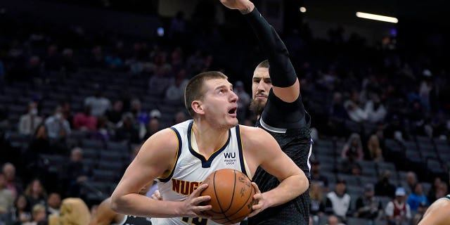 Denver Nuggets center Nikola Jokic drives to the basket against Sacramento Kings center Alex Len during the first half of an NBA basketball game in Sacramento, Calif., Wednesday, March 9, 2022.